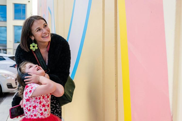 adult and child wearing headphones looking up at mural